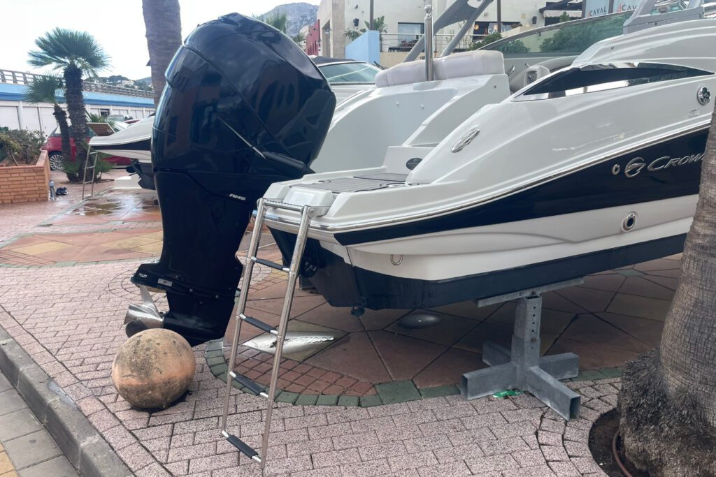 Escalera de popa de acero inoxidable plegable instalada en lancha Crownline con motor fueraborda negro