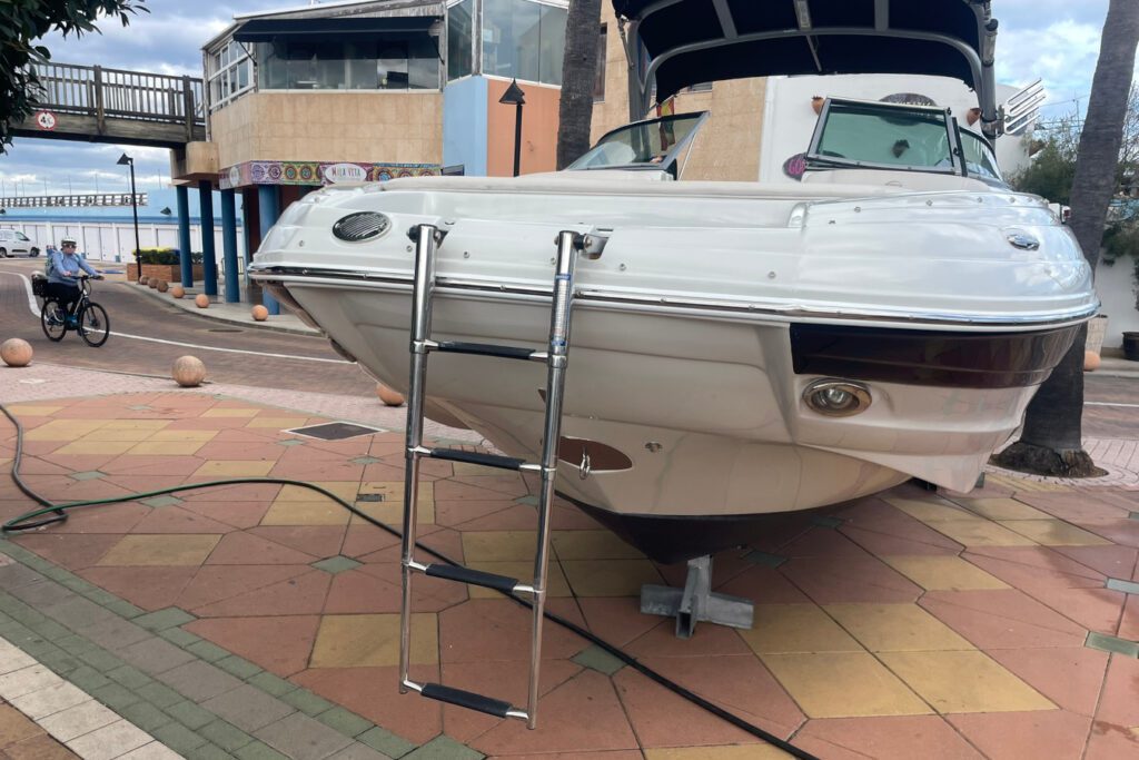 Escalera de proa de acero inoxidable E2XS instalada en lancha motora blanca amarrada en puerto deportivo